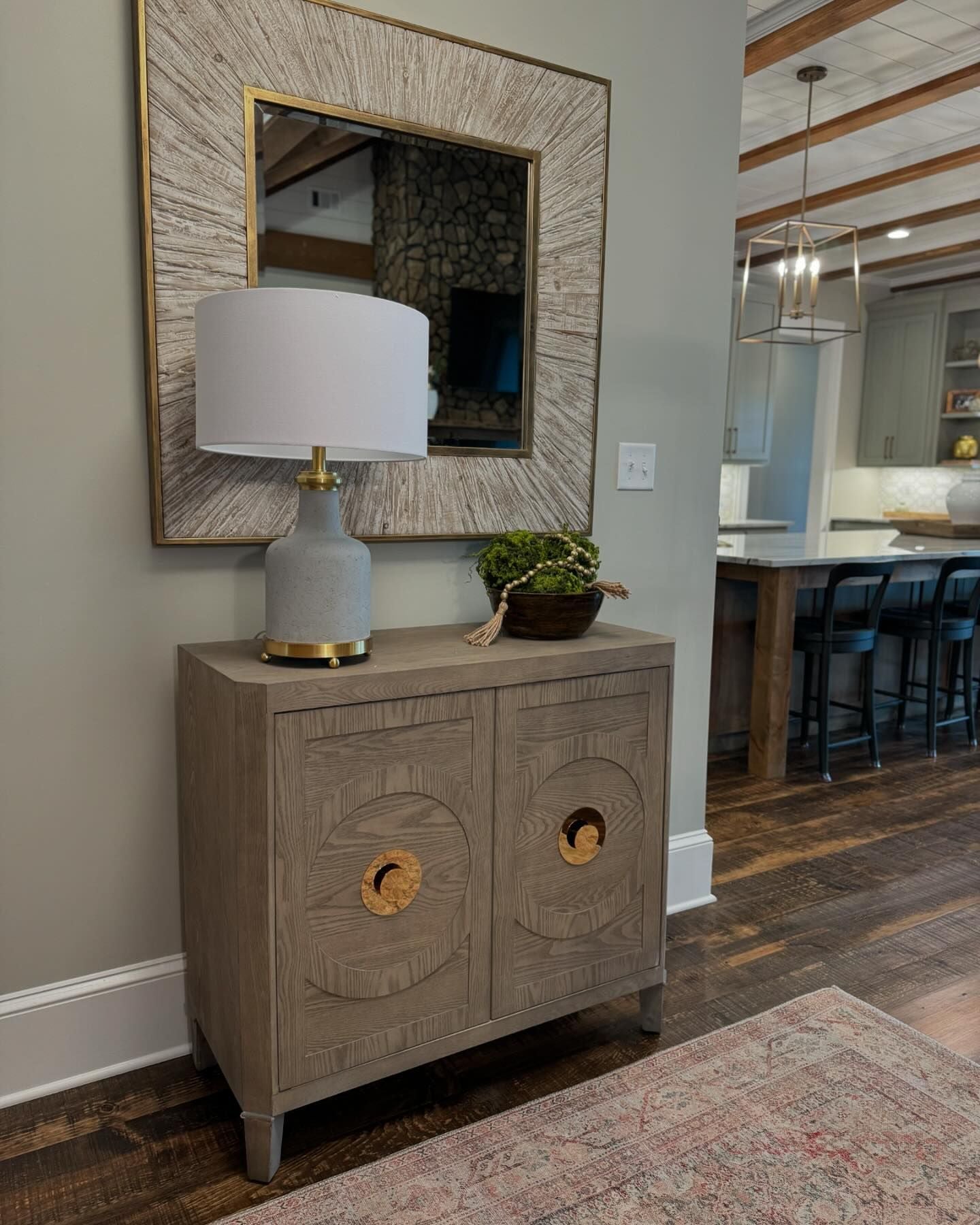 Entry way decorated with a lamp, mirror and floral accent.
